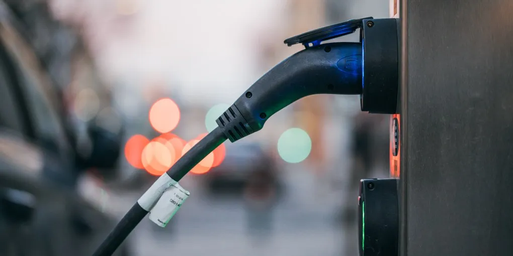 Acercamiento de un auto eléctrico conectado a una estación de carga de corriente alterna